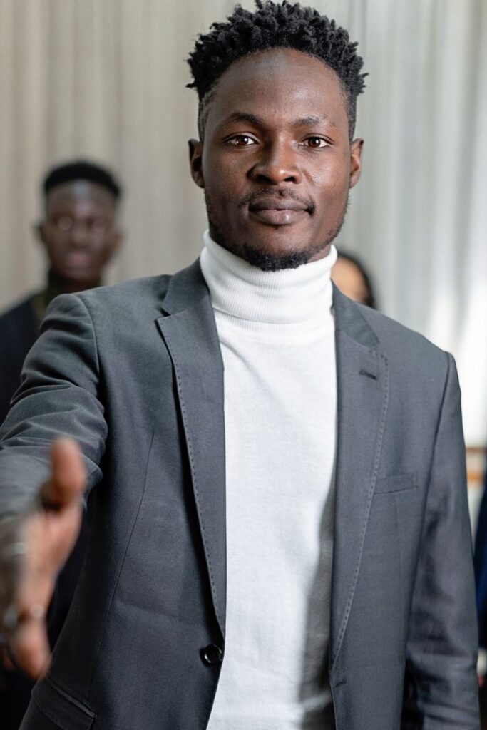 Portrait of a confident black businessman offering a handshake indoors.